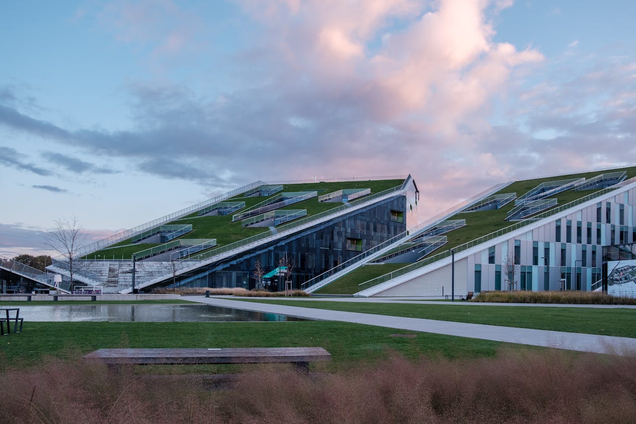 A stunning example of eco-friendly architecture with grass rooftops illuminated by the sunset.